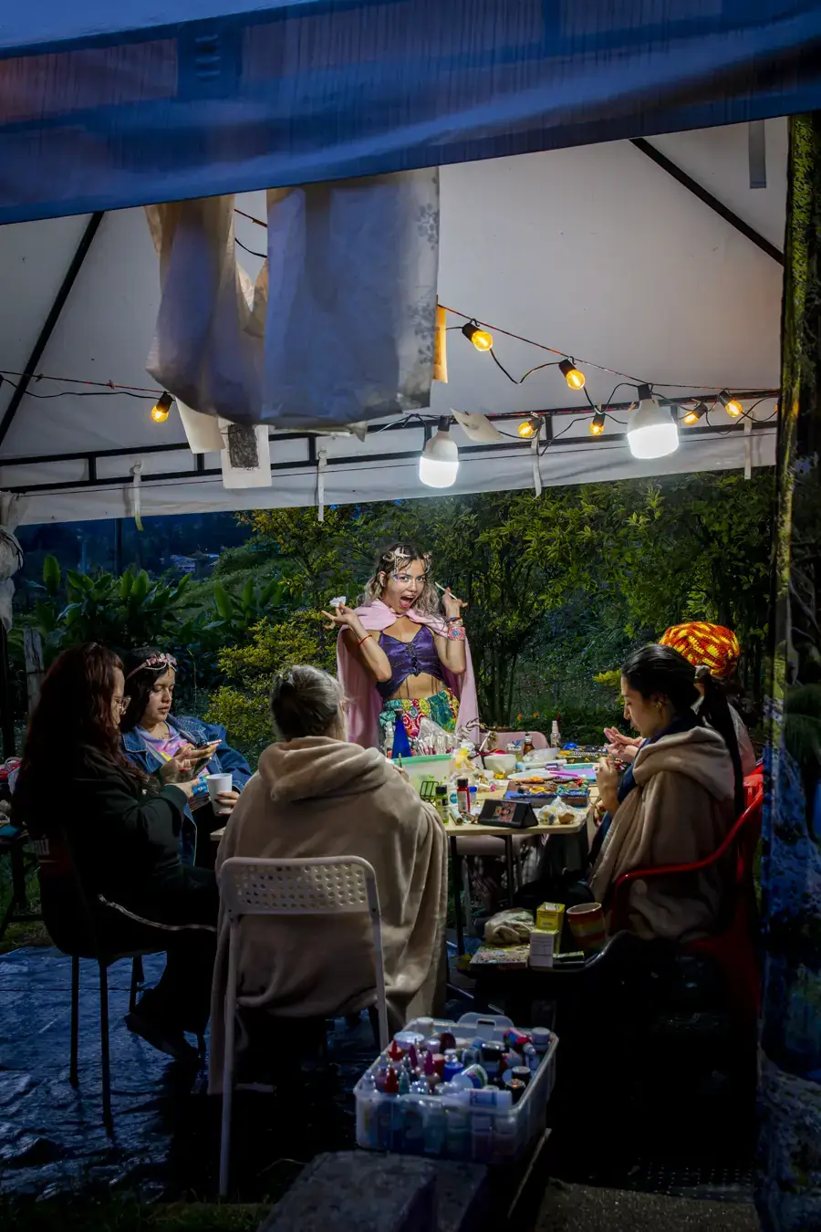 Mesa de taller bajo la carpa, de noche, con Uva al fondo