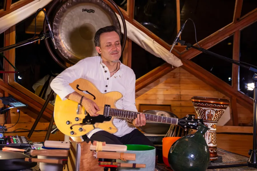 Mauro D'León toca una guitarra amarilla de caja con sus instrumentos alrededor